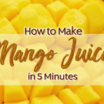 A close-up image of a glass filled with vibrant orange mango juice. A slice of fresh mango and a sprig of mint garnish the rim of the glass.